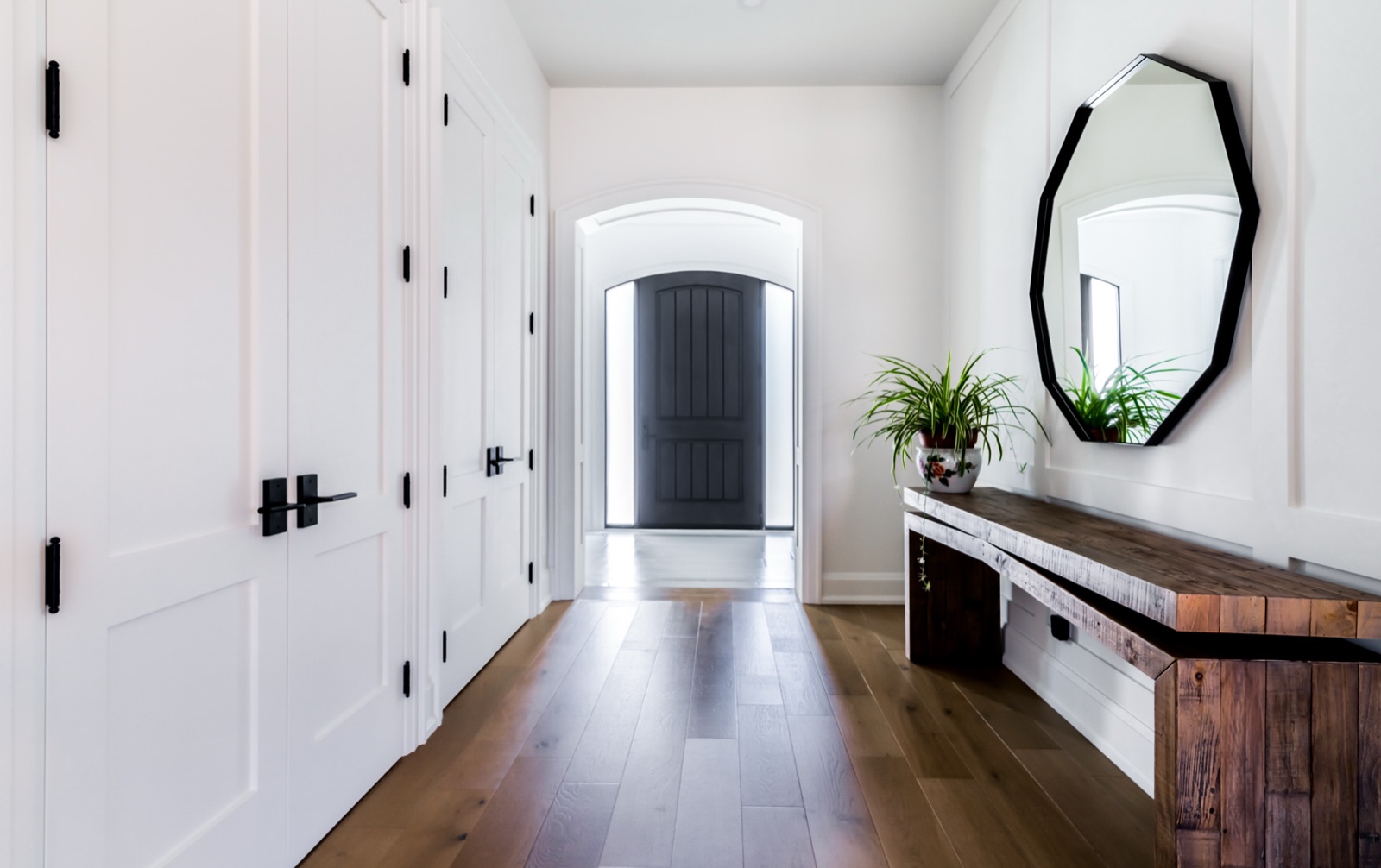 Bright entry hall with reclaimed wood bench and black-framed mirror