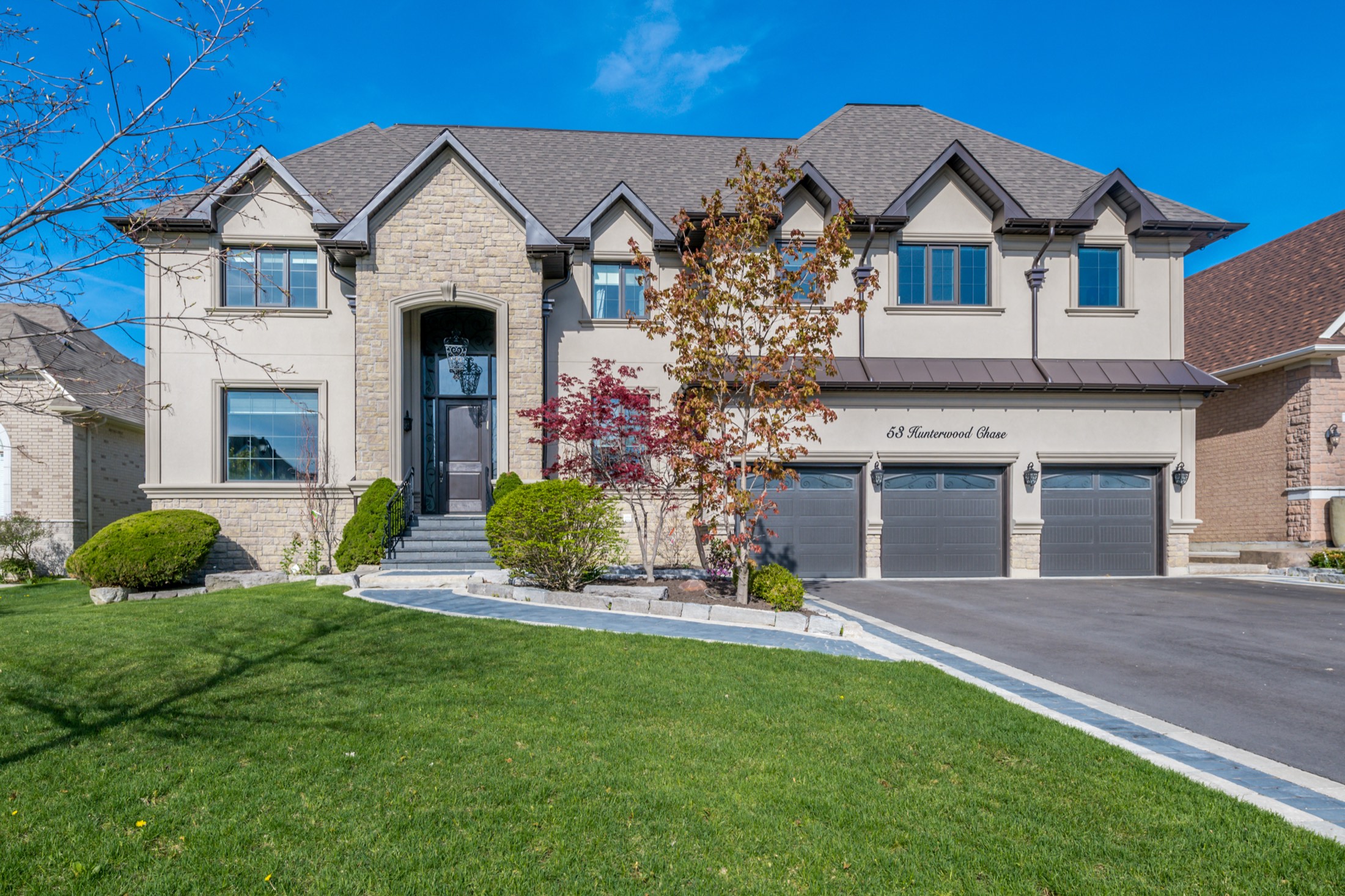 A grand custom-built stone and stucco home with manicured landscaping