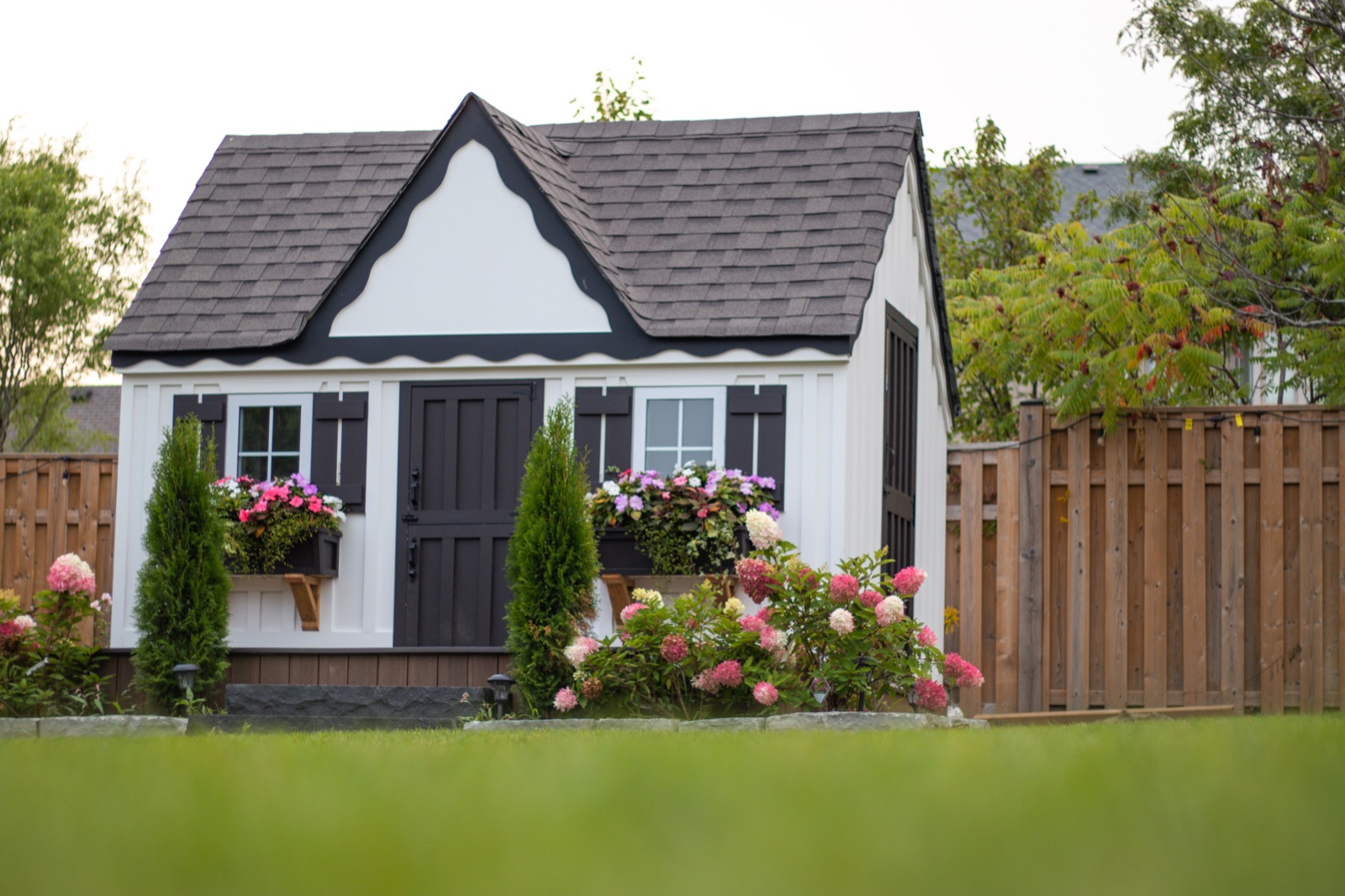 Tudor-style luxury playhouse with flower boxes and picket details