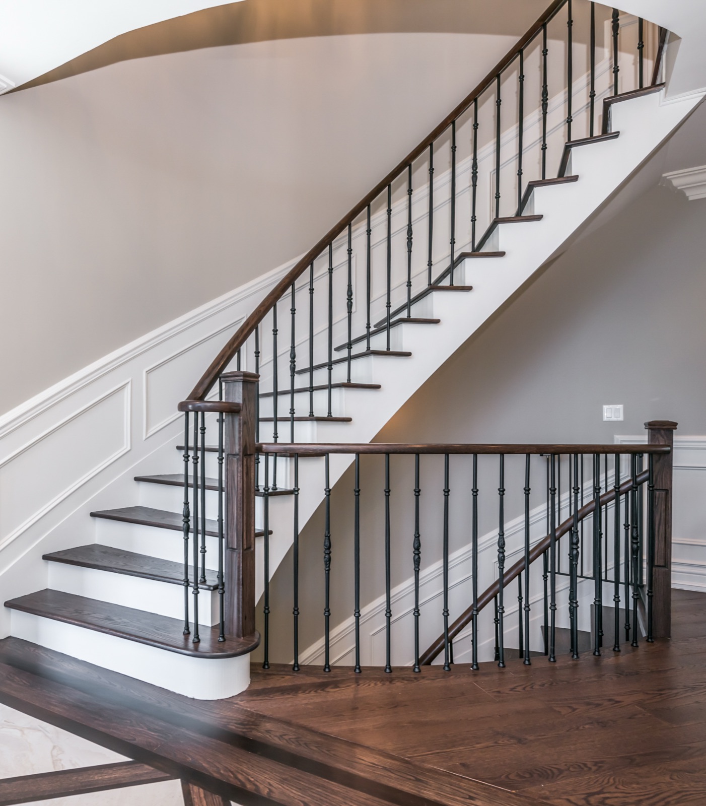 A hand-built curved oak staircase with wrought-iron balusters